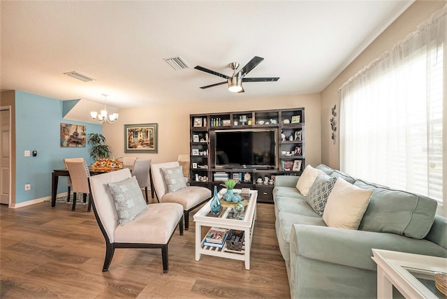 living room with ceiling fan with notable chandelier and hardwood / wood-style flooring