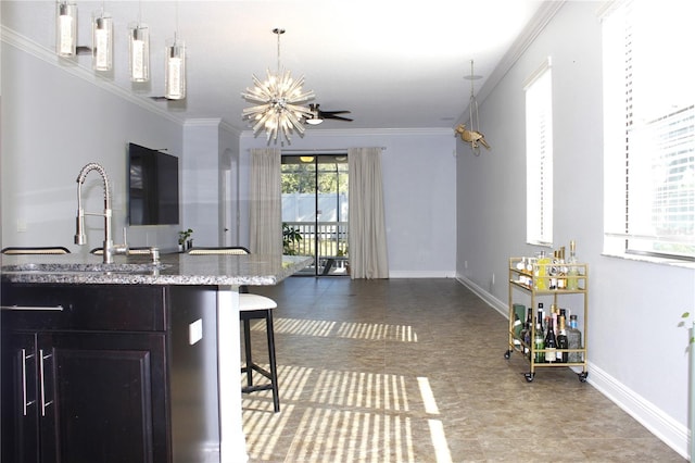 kitchen featuring sink, a notable chandelier, decorative light fixtures, a kitchen bar, and ornamental molding