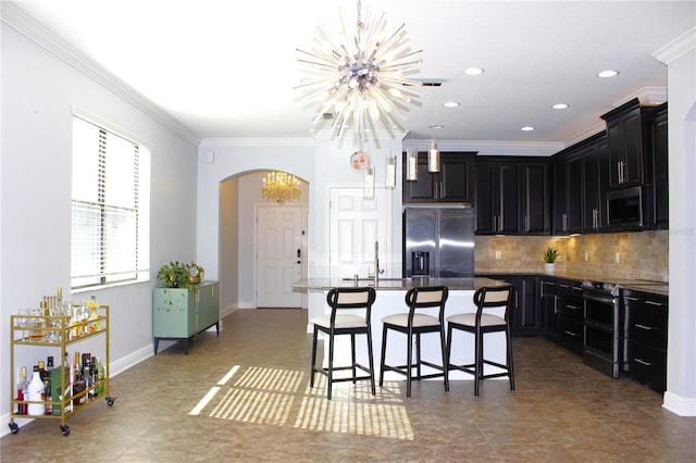 kitchen featuring stainless steel fridge with ice dispenser, a notable chandelier, an island with sink, a kitchen bar, and ornamental molding