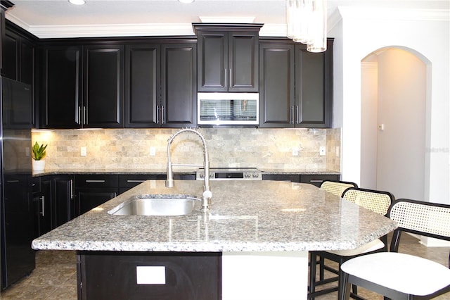 kitchen with a kitchen breakfast bar, sink, ornamental molding, and a kitchen island with sink