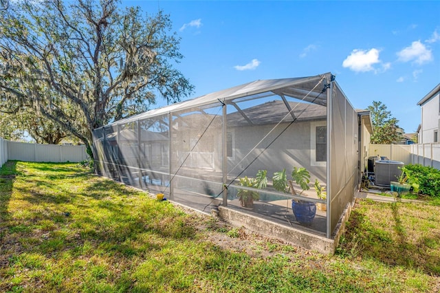 back of house with glass enclosure, a fenced backyard, cooling unit, and a yard