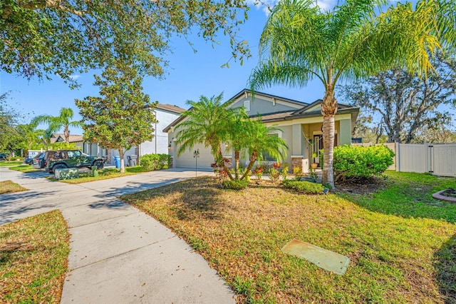 view of front facade with a garage, fence, driveway, stucco siding, and a front lawn