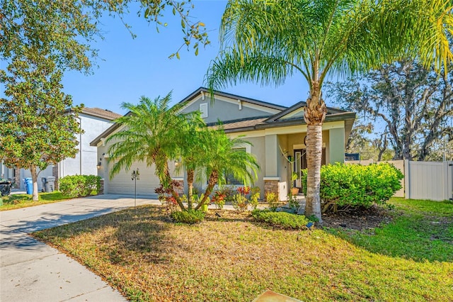 view of front of property featuring a garage, concrete driveway, stucco siding, fence, and a front yard