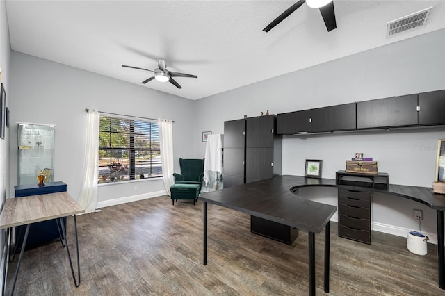 home office featuring dark wood-style floors, ceiling fan, visible vents, and baseboards