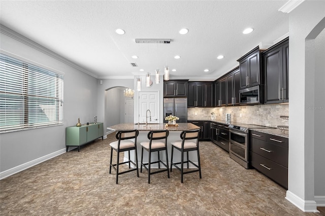 kitchen featuring appliances with stainless steel finishes, arched walkways, a sink, and ornamental molding