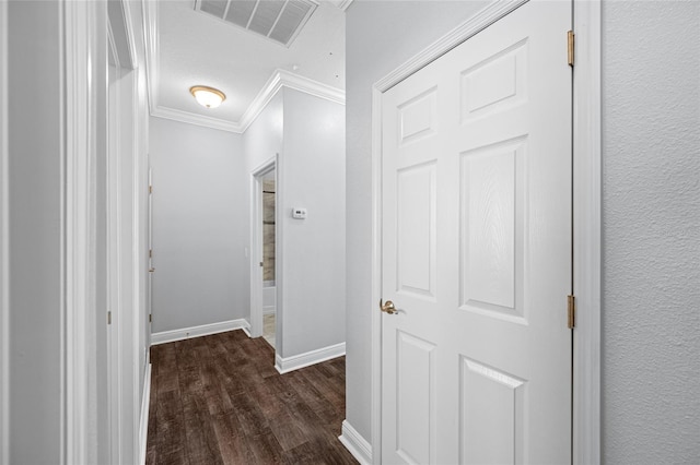 hallway featuring dark wood-style floors, baseboards, visible vents, and crown molding