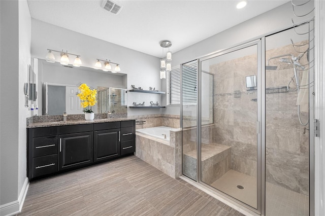 bathroom featuring visible vents, a stall shower, vanity, and a bath