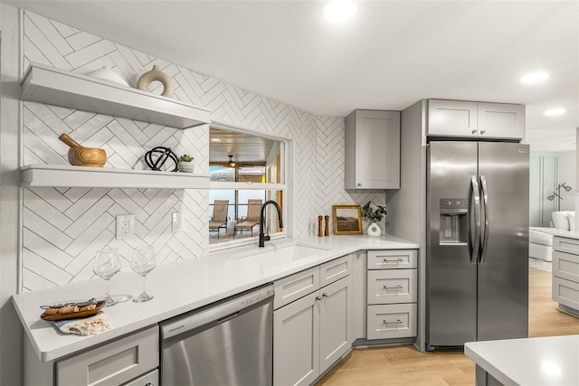 kitchen featuring gray cabinetry, sink, decorative backsplash, appliances with stainless steel finishes, and light hardwood / wood-style floors