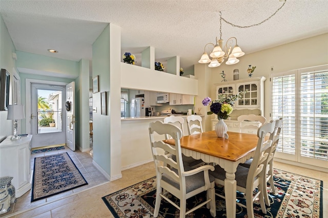 tiled dining room with a notable chandelier and a textured ceiling