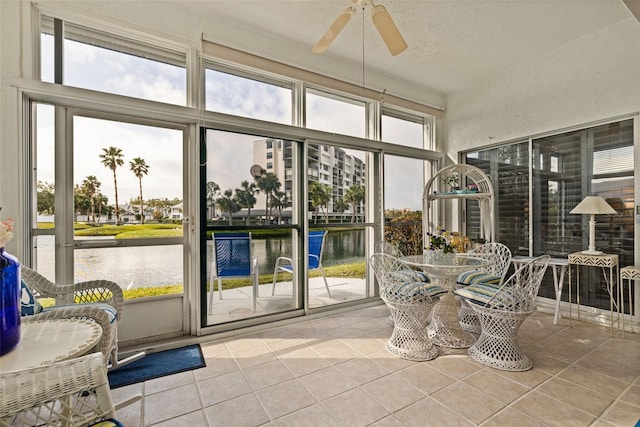 sunroom / solarium with ceiling fan and a water view