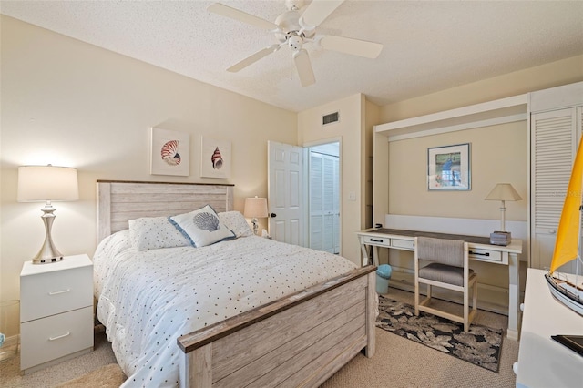 bedroom featuring ceiling fan, light colored carpet, a textured ceiling, and a closet