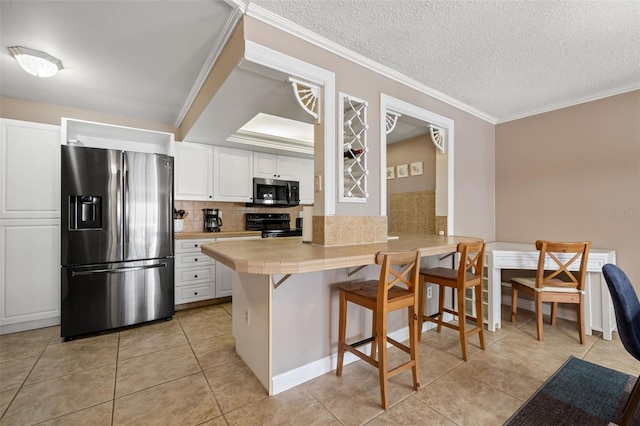 kitchen featuring kitchen peninsula, a breakfast bar, white cabinets, and stainless steel appliances