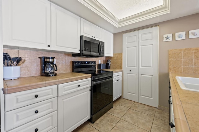 kitchen with tile countertops, ornamental molding, black range with electric cooktop, light tile patterned flooring, and white cabinetry