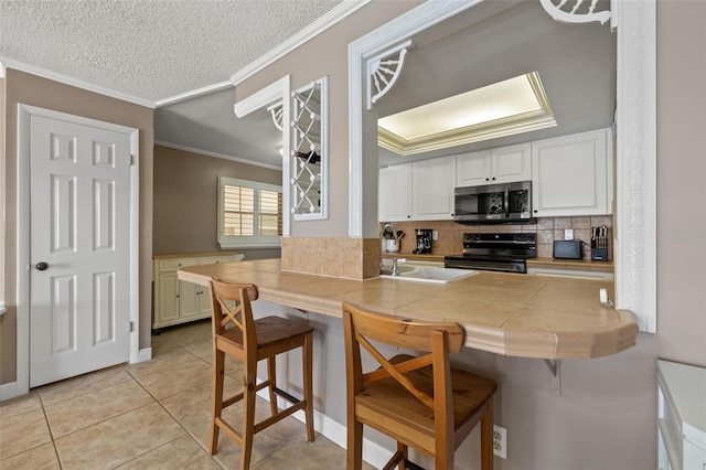 kitchen with tile countertops, black range oven, a textured ceiling, a kitchen bar, and white cabinetry