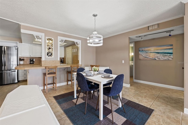 dining area with ornamental molding, a textured ceiling, light tile patterned floors, and an inviting chandelier