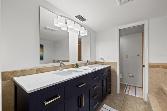 bathroom featuring tile patterned flooring, vanity, toilet, and tile walls