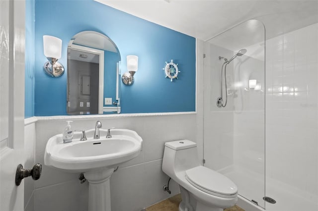 bathroom with tiled shower, toilet, and tile walls