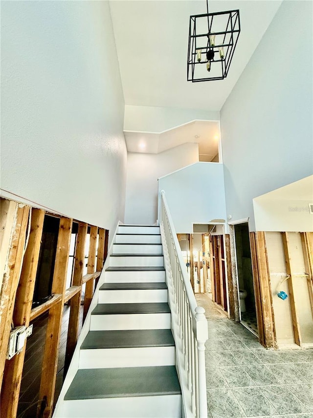 stairs featuring a chandelier and a towering ceiling