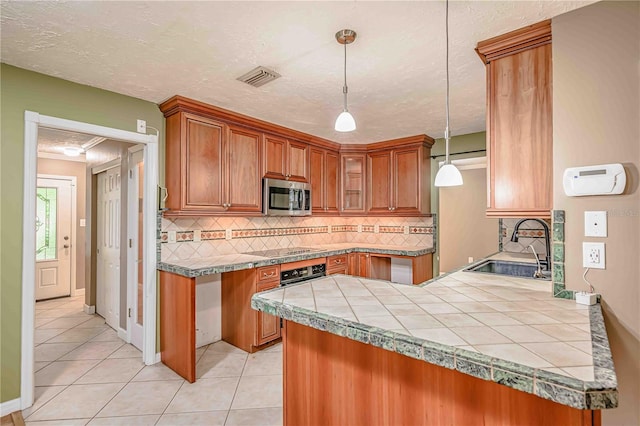 kitchen featuring sink, light tile patterned floors, tasteful backsplash, decorative light fixtures, and kitchen peninsula