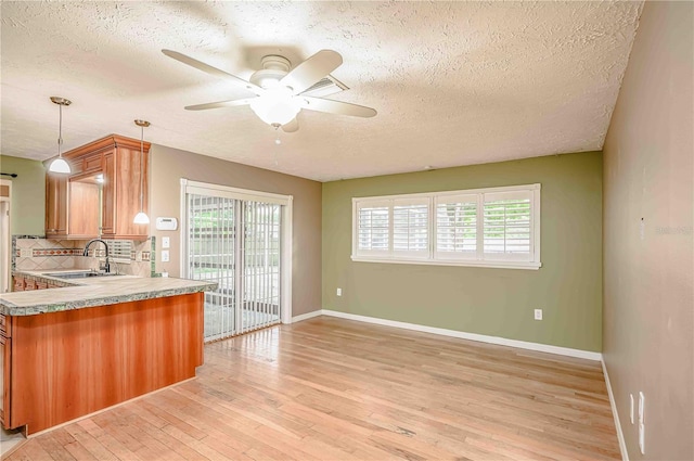 kitchen with a textured ceiling, a healthy amount of sunlight, light wood-type flooring, and sink