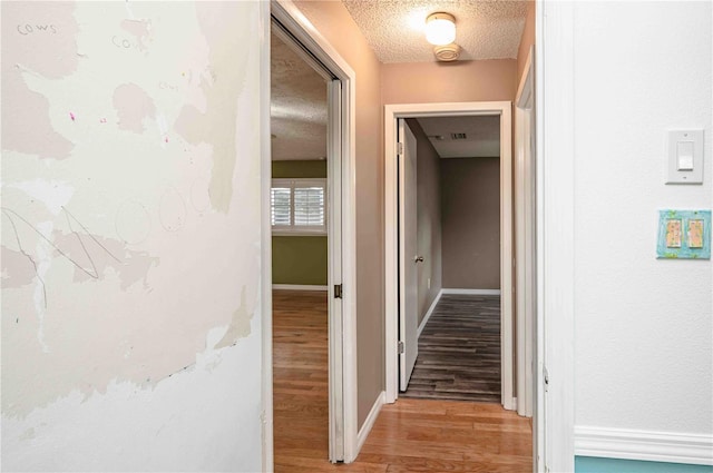 hall featuring a textured ceiling and light wood-type flooring