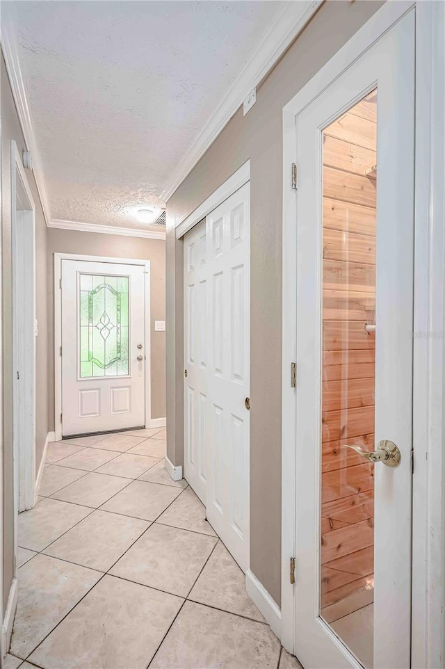 doorway to outside featuring ornamental molding, a textured ceiling, and light tile patterned floors