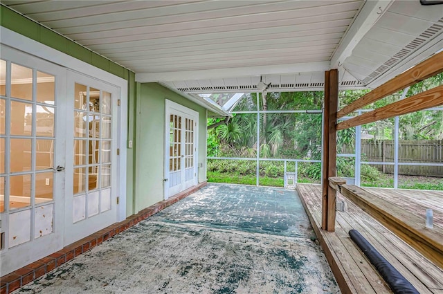 sunroom / solarium featuring beam ceiling, french doors, and plenty of natural light