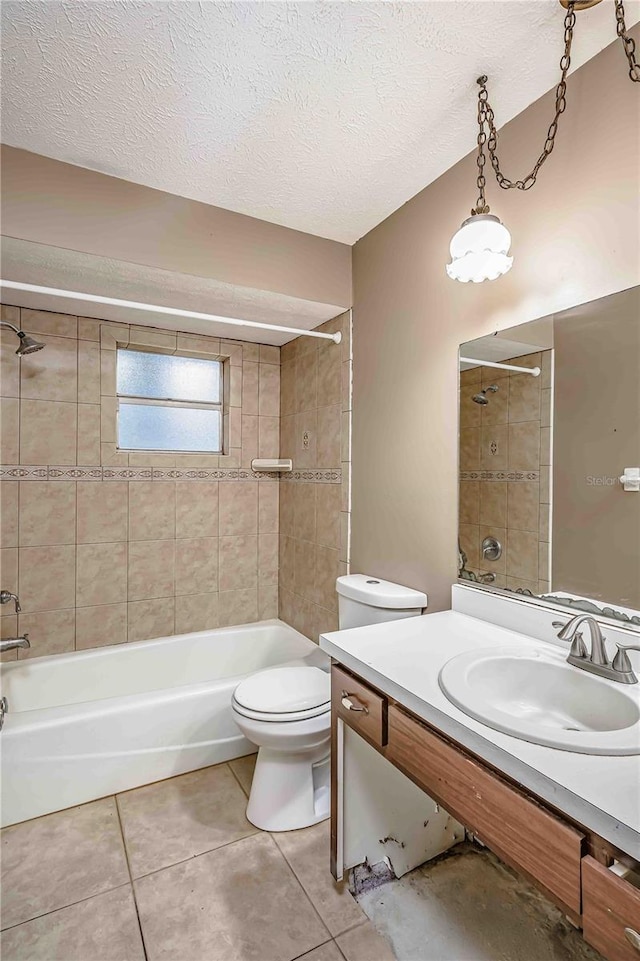 full bathroom featuring vanity, tile patterned flooring, tiled shower / bath combo, toilet, and a textured ceiling