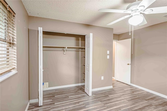 unfurnished bedroom featuring ceiling fan, a closet, light hardwood / wood-style floors, and a textured ceiling