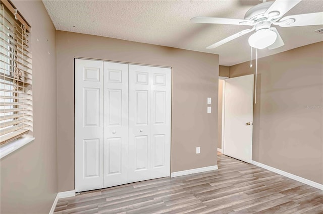 unfurnished bedroom featuring a textured ceiling, light wood-type flooring, a closet, and ceiling fan