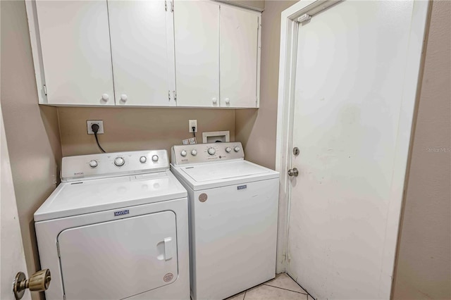 laundry room featuring washing machine and dryer, light tile patterned flooring, and cabinets