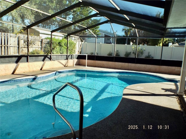 view of pool with glass enclosure and a patio area