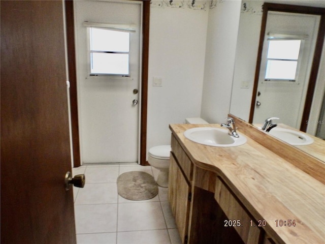 bathroom with toilet, vanity, tile patterned floors, and a wealth of natural light