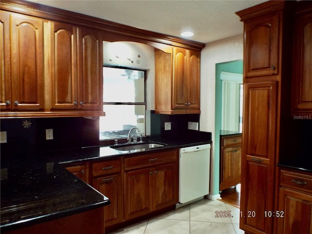 kitchen featuring sink, dark stone countertops, dishwasher, and light tile patterned flooring