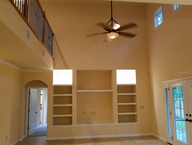 interior space with built in shelves, ceiling fan, crown molding, and a high ceiling