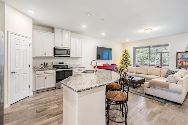 kitchen with light wood-type flooring, stainless steel appliances, white cabinetry, and sink