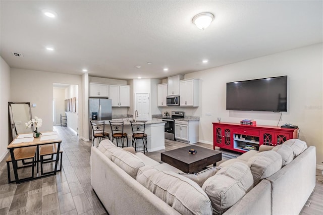 living room with light hardwood / wood-style flooring and sink