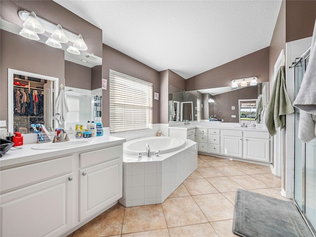 bathroom with tile patterned flooring, vaulted ceiling, separate shower and tub, and vanity