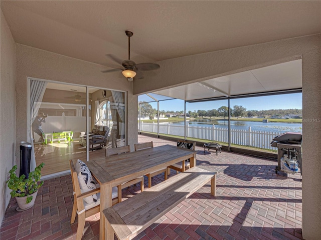 sunroom / solarium with ceiling fan and a water view