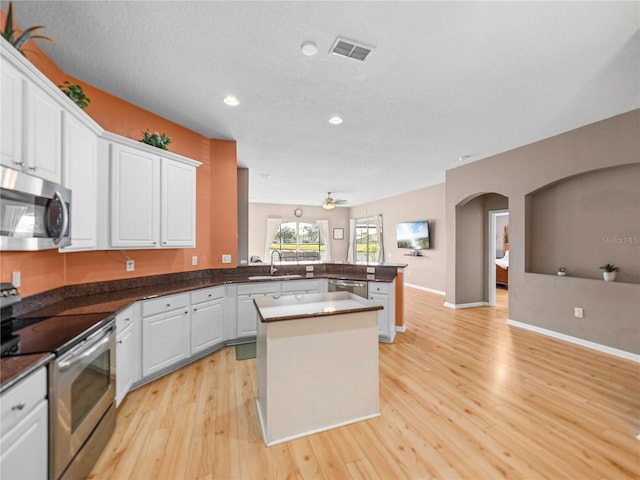 kitchen with stainless steel appliances, light wood-type flooring, a center island, kitchen peninsula, and white cabinets