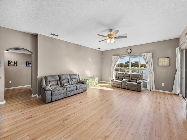 living room featuring a textured ceiling, ceiling fan, and light hardwood / wood-style flooring