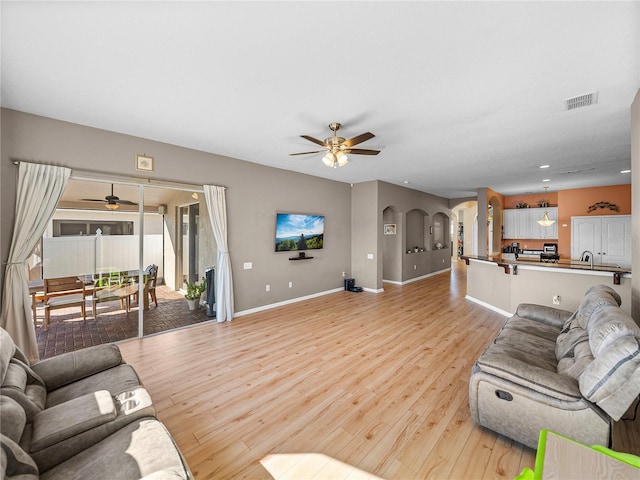 living room with sink, ceiling fan, light hardwood / wood-style floors, and plenty of natural light