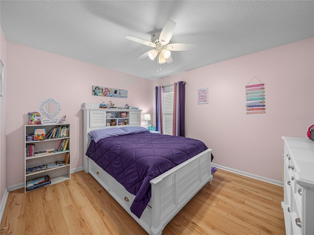 bedroom featuring ceiling fan, light hardwood / wood-style flooring, and a textured ceiling