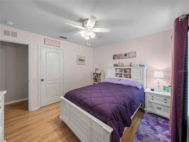 bedroom with a textured ceiling, ceiling fan, light hardwood / wood-style flooring, and a closet