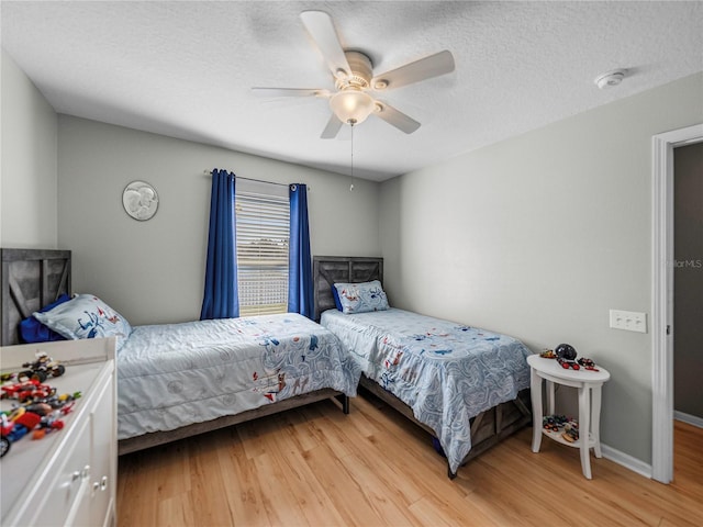 bedroom with ceiling fan, a textured ceiling, and wood-type flooring