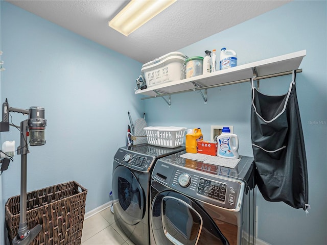 laundry area featuring a textured ceiling, light tile patterned flooring, and washer and clothes dryer