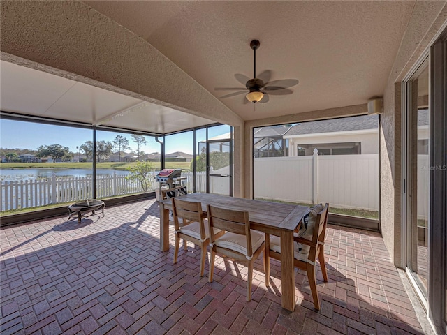 sunroom with ceiling fan, vaulted ceiling, a healthy amount of sunlight, and a water view