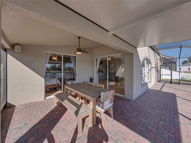 view of patio with ceiling fan and glass enclosure