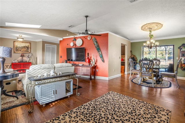 living room with vaulted ceiling with skylight, ceiling fan with notable chandelier, dark hardwood / wood-style flooring, and ornamental molding