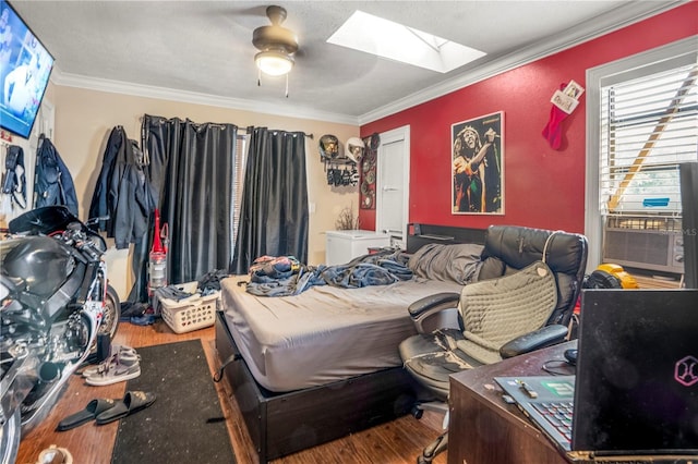 bedroom with a skylight, ceiling fan, crown molding, cooling unit, and hardwood / wood-style flooring